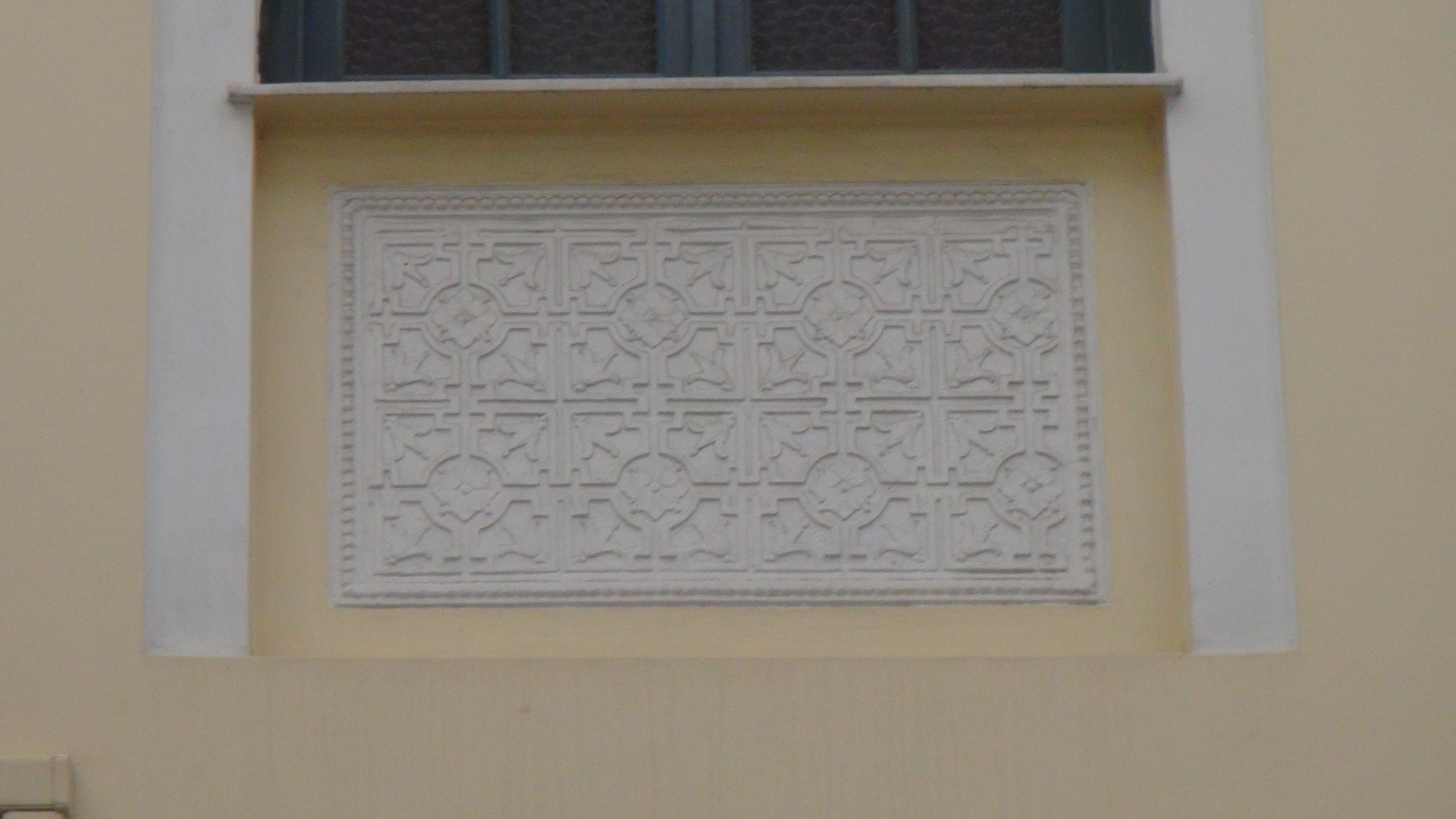 Decorative engraved plaque under the window of the upper floor at the side of the building