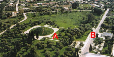 Αεροφωτογραφία του αρχαιολογικού χώρου πριν τη διεύρυνση των ορίων του (2004). Διακρίνονται οι πλακοστρώσεις γύρω από τον Τύμβο (A) καθώς και το τουριστικό περίπτερο ΕΟΤ (B) πριν την καθαίρεσή τους