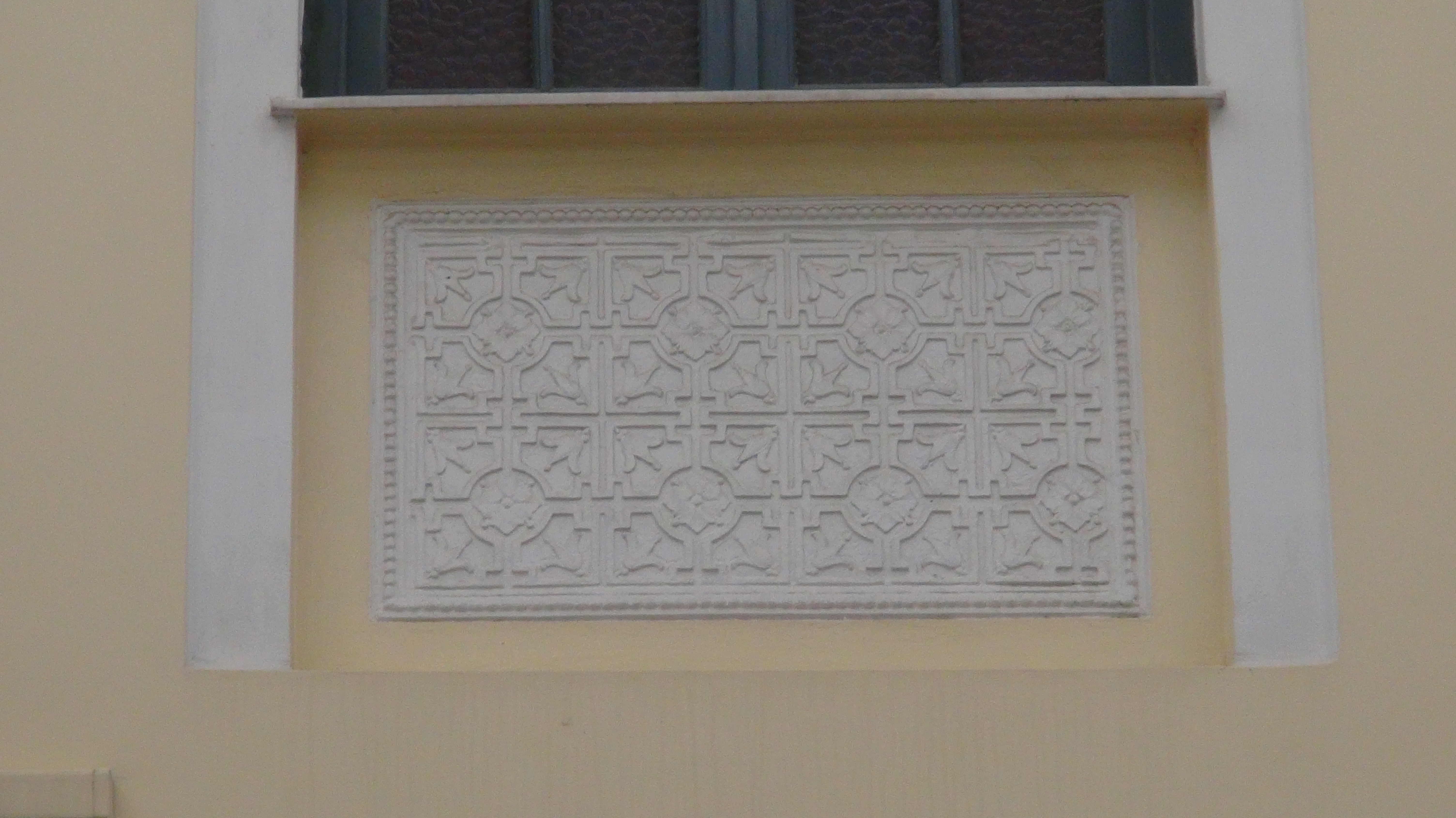 Decorative engraved plaque under the window of the upper floor at the side of the building
